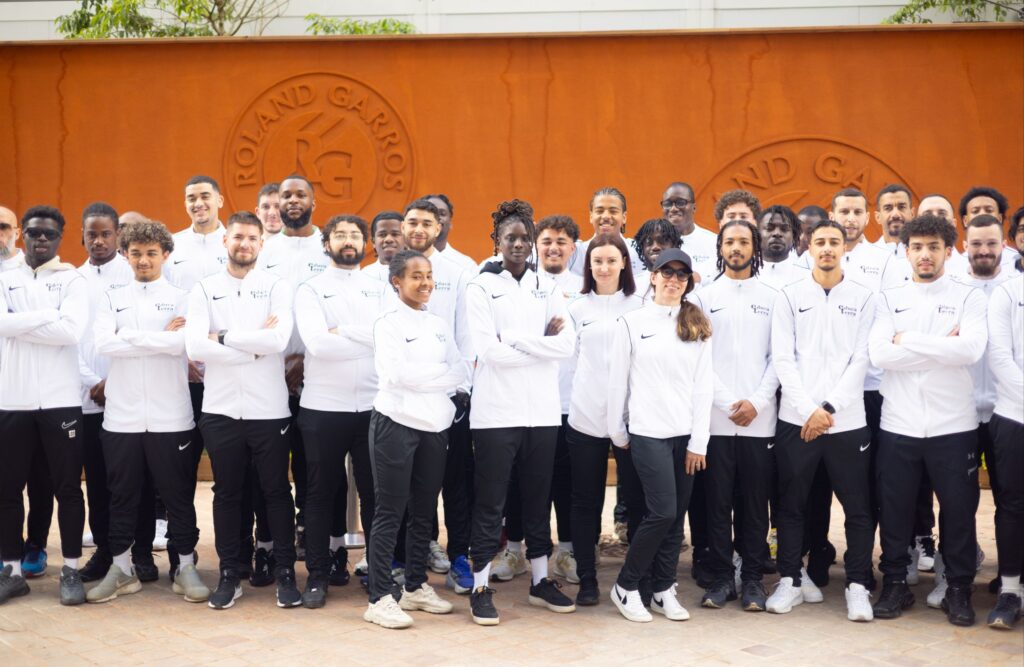 Les stagiaires d'Educaterra tenant la pose devant le mur de terre battue de Roland Garros